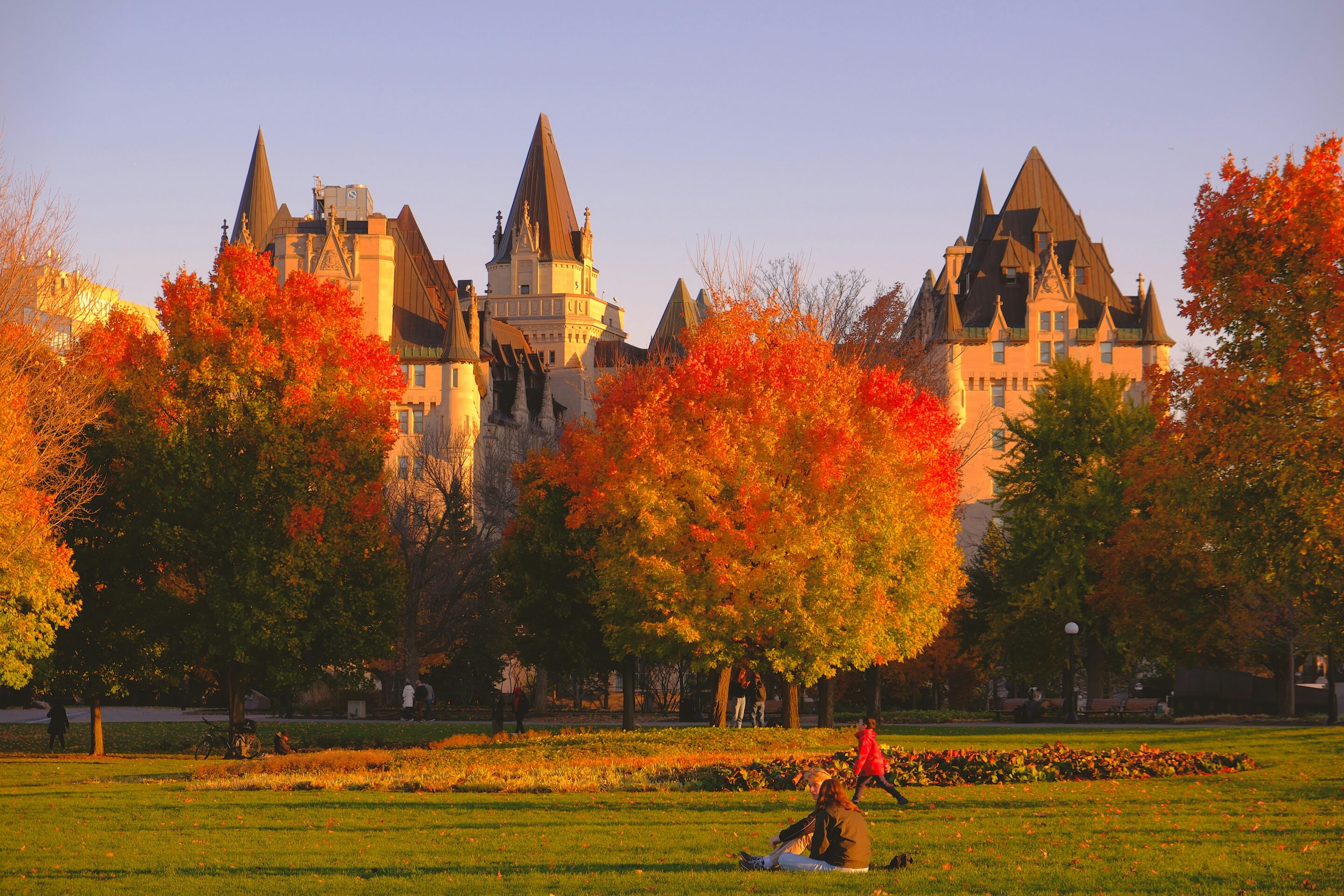 Een groep mensen zittend in een veld voor een kasteel tijdens het gouden uur
