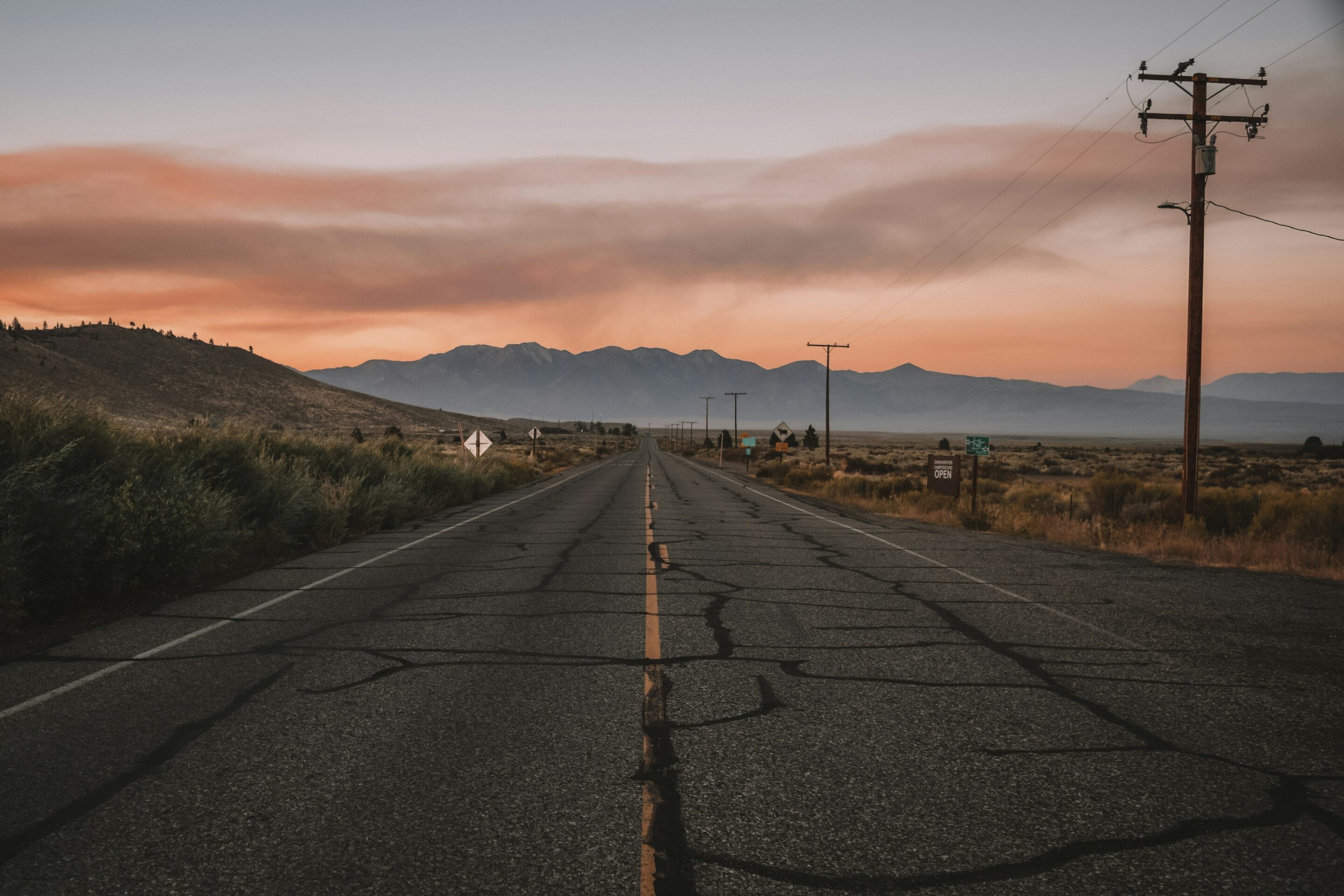 Roadtrip oude weg met telegraafpalen richting te bergen bij zonsondergang